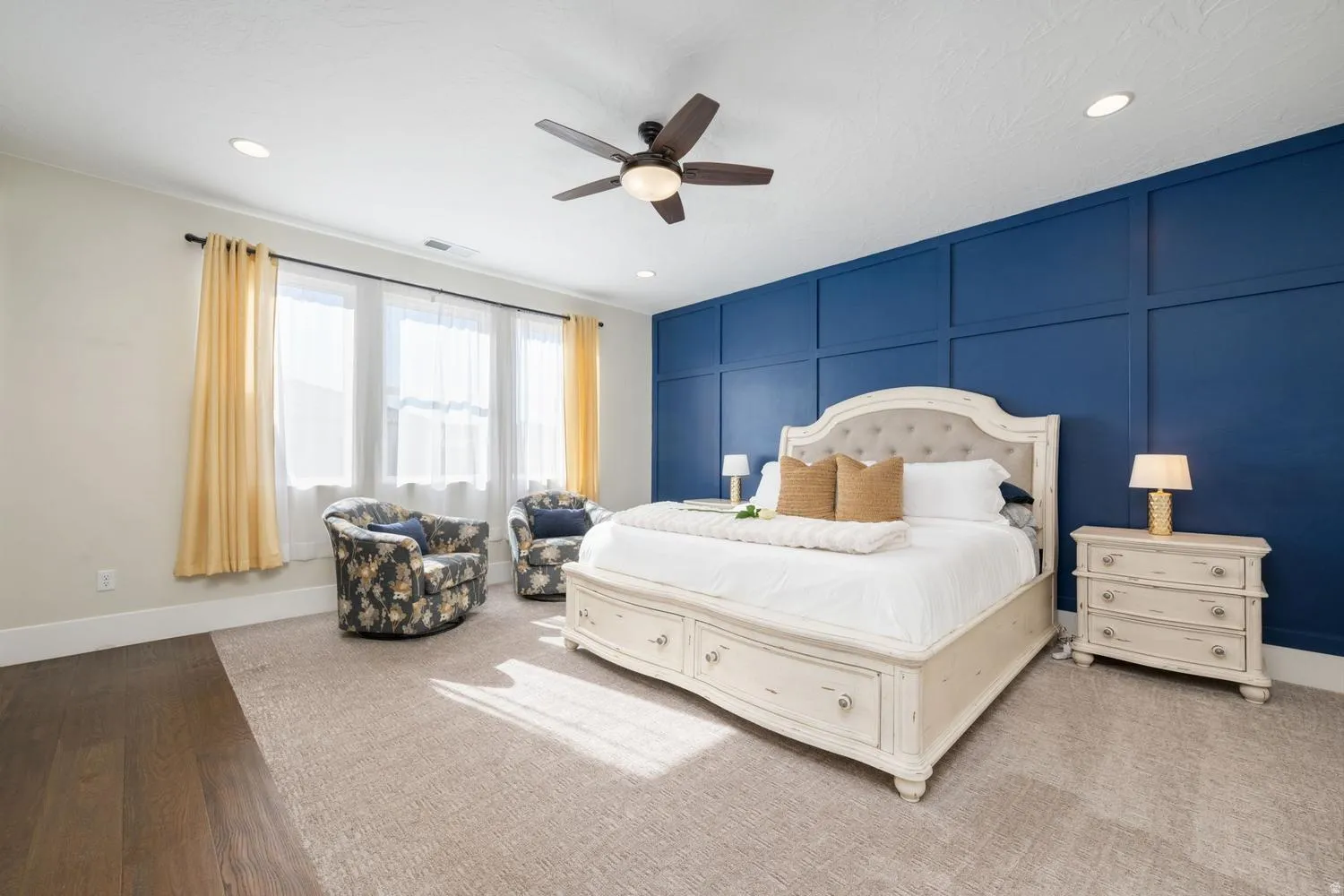 Spacious room featuring a prominent blue accent wall with paneling, multiple windows, recessed lighting, and a ceiling fan