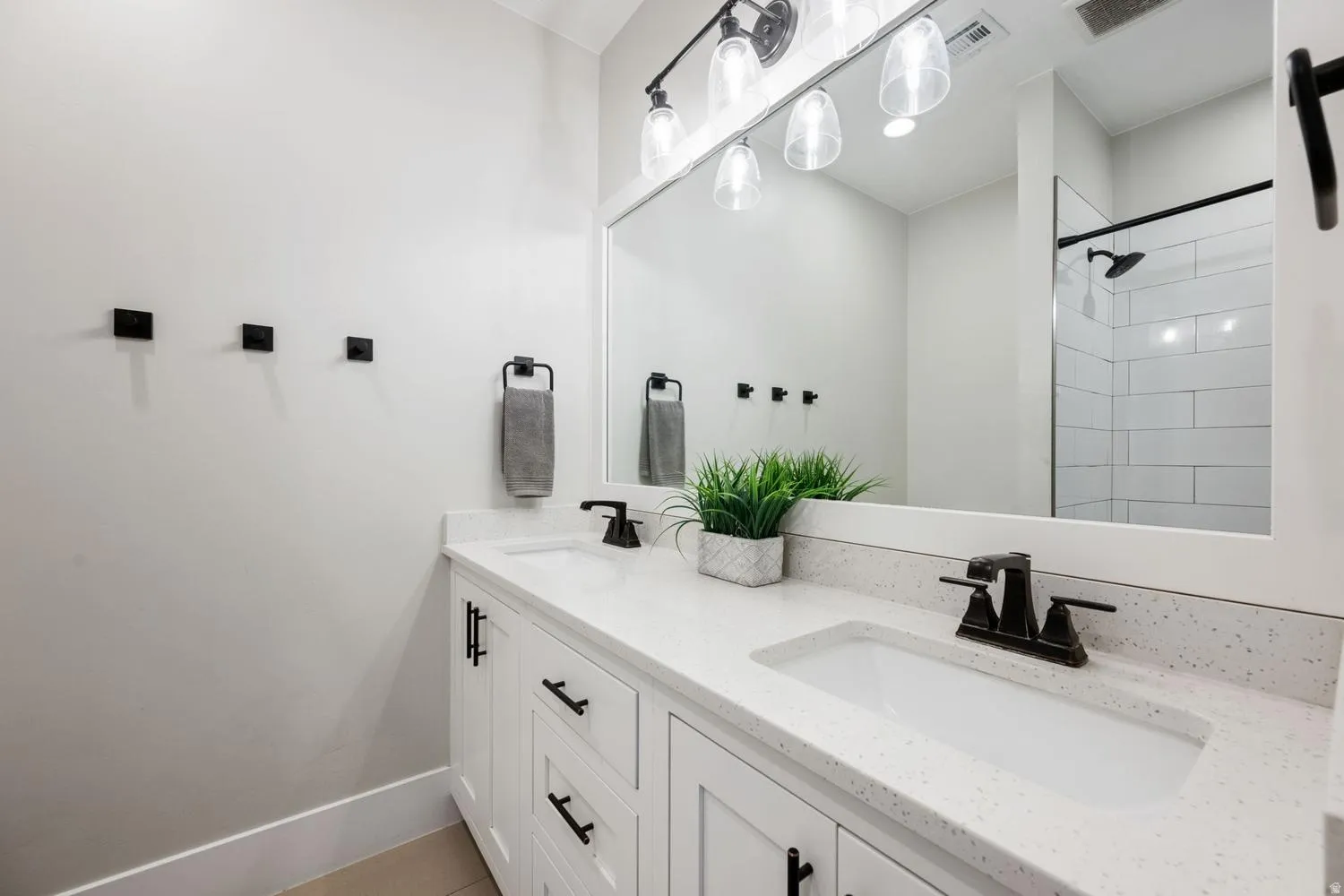 Dual vanity with white cabinetry and integrated sinks, complemented by dark-finish hardware and faucets
