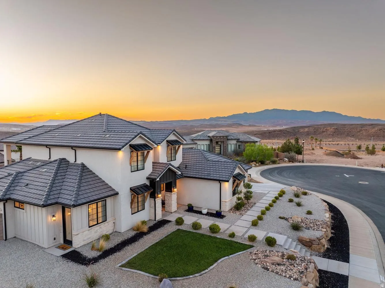 Contemporary stucco home featuring a dark tile roof, black-framed windows, and stone accents