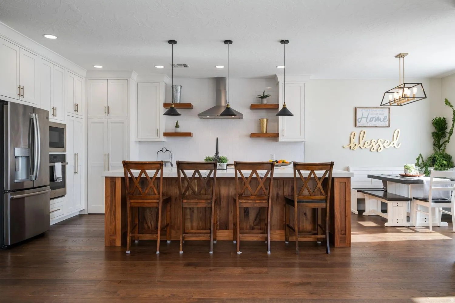 Open-concept kitchen featuring white shaker cabinetry, stainless steel appliances, and a wood-finish island with a light-toned countertop