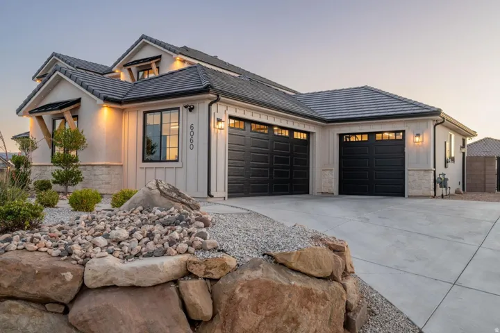 Modern farmhouse exterior featuring board and batten siding, stone accents, and a dark tile roof