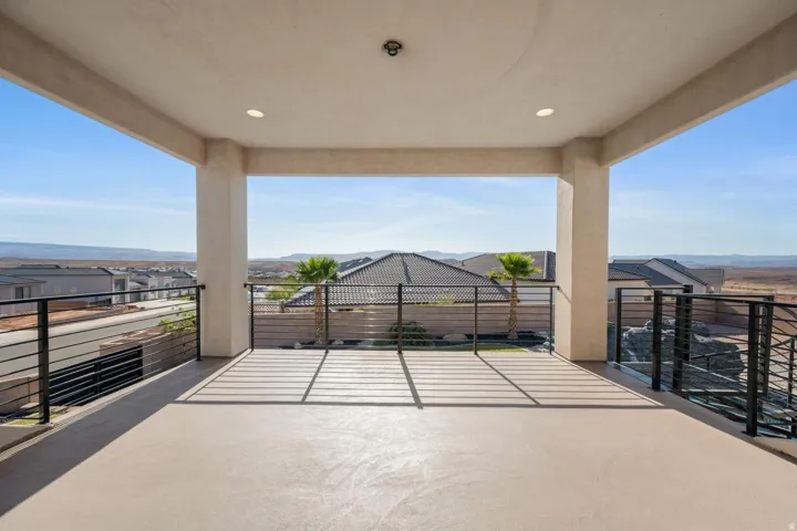 Spacious covered patio featuring a concrete floor, recessed lighting, and black metal railings