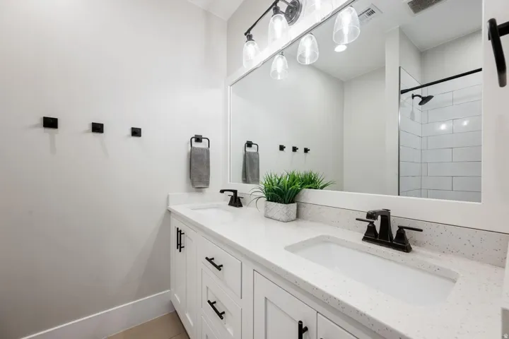 Dual vanity with white cabinetry and integrated sinks, complemented by dark-finish hardware and faucets