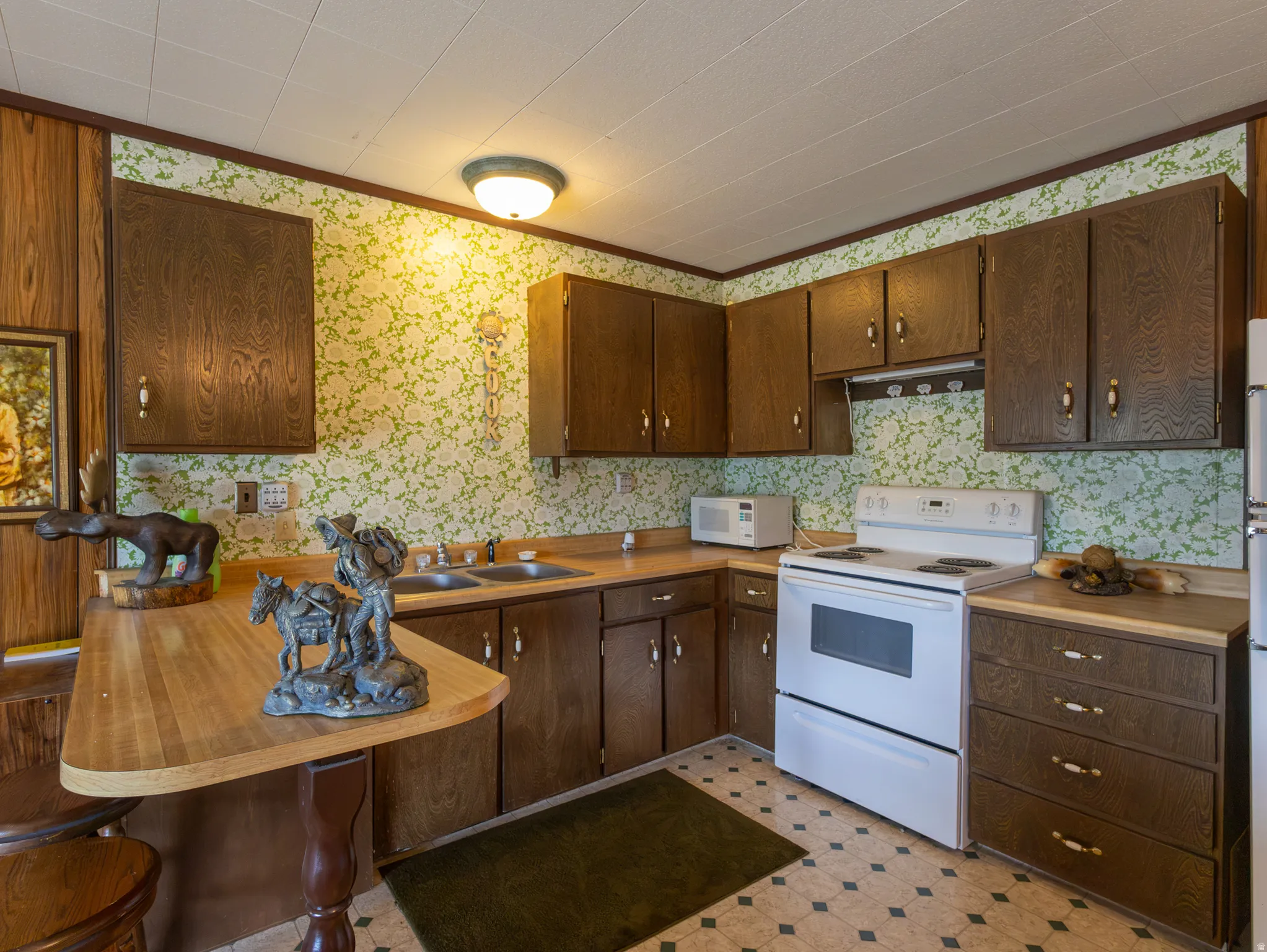 Kitchen featuring wood-finish cabinetry, a double basin sink, and a built-in breakfast bar