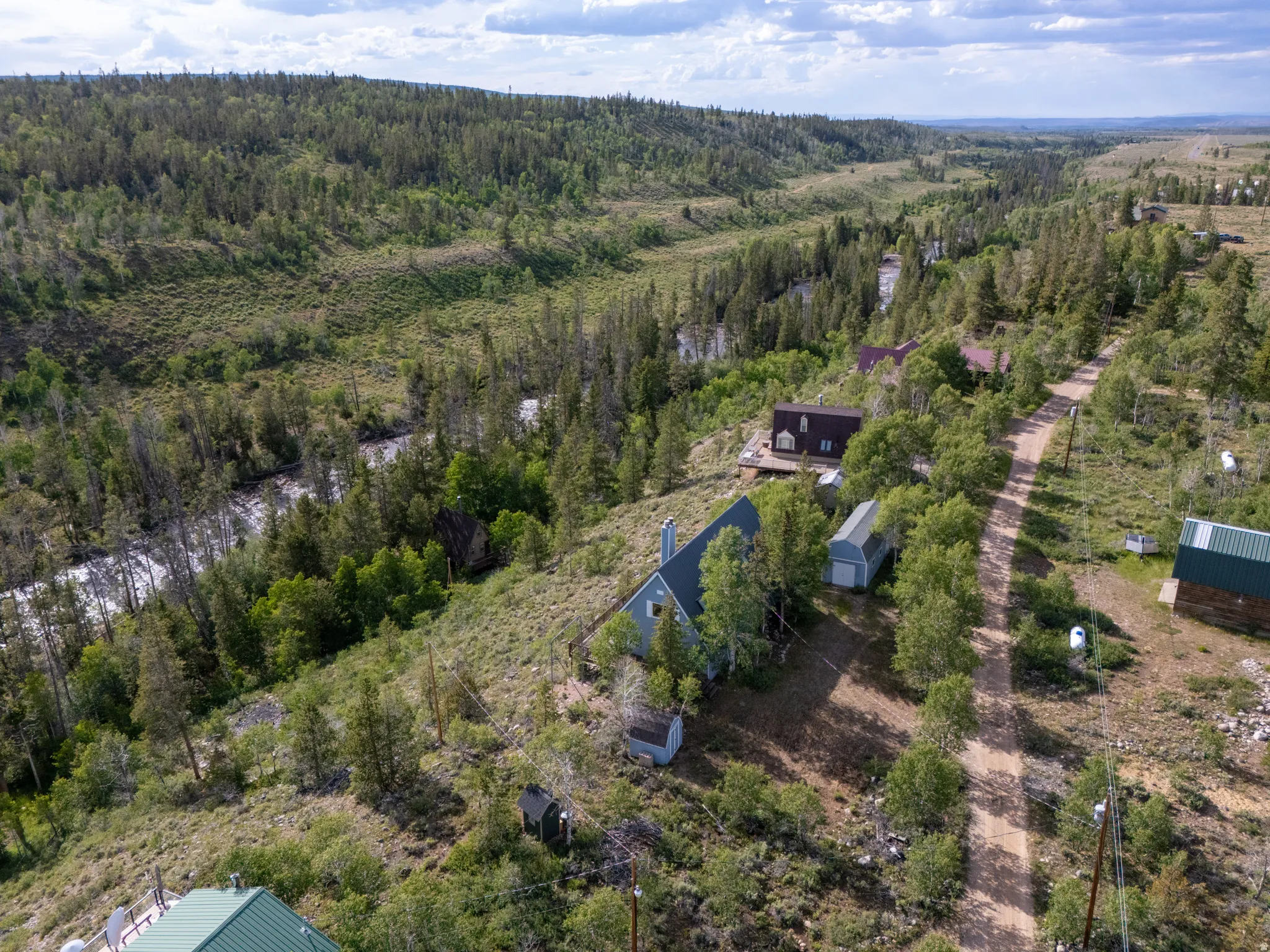 Expansive property featuring a winding river, mature evergreen trees, and a gravel road