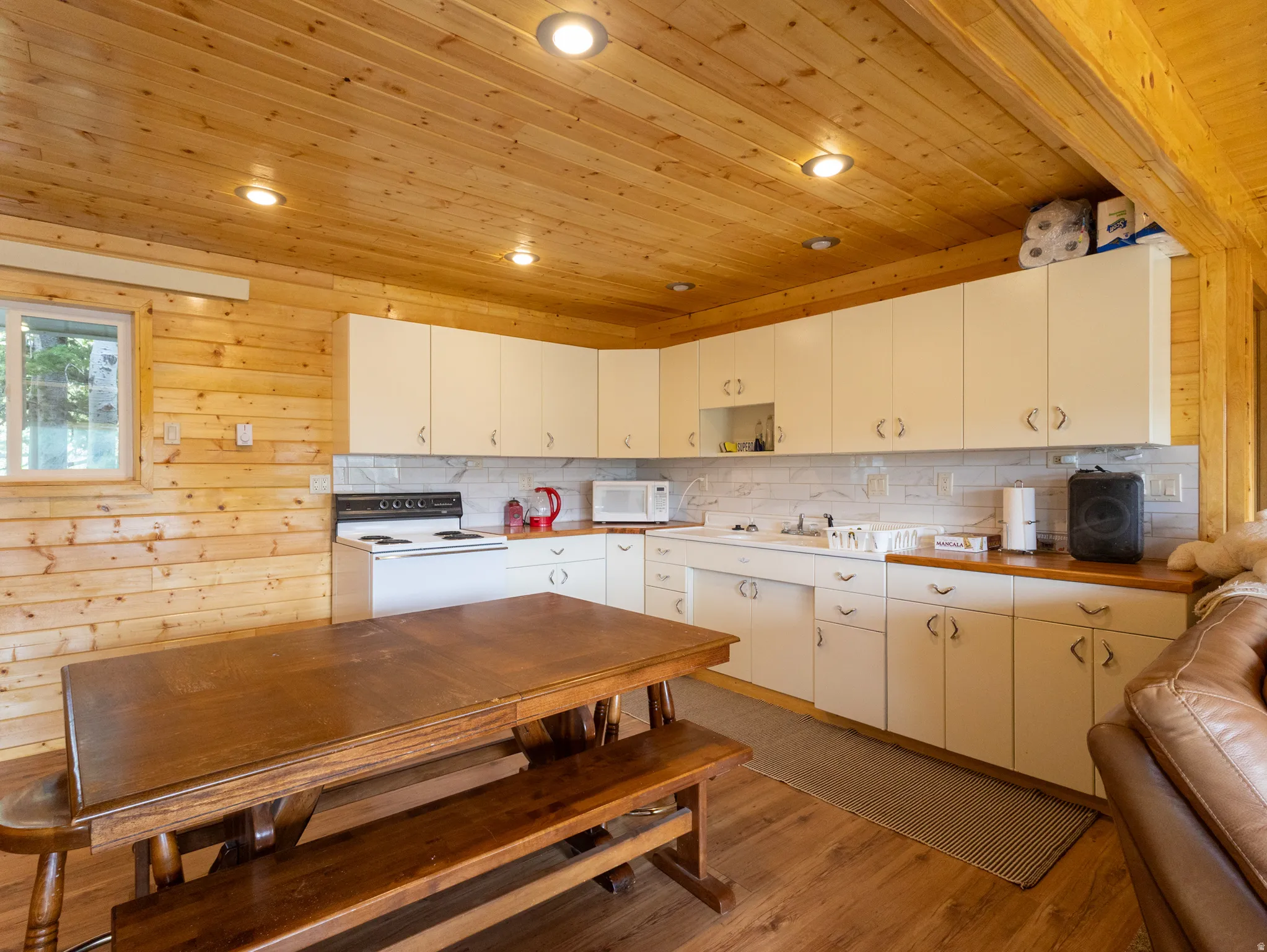 Kitchen area featuring wood paneling throughout, recessed lighting, and wood-finish flooring