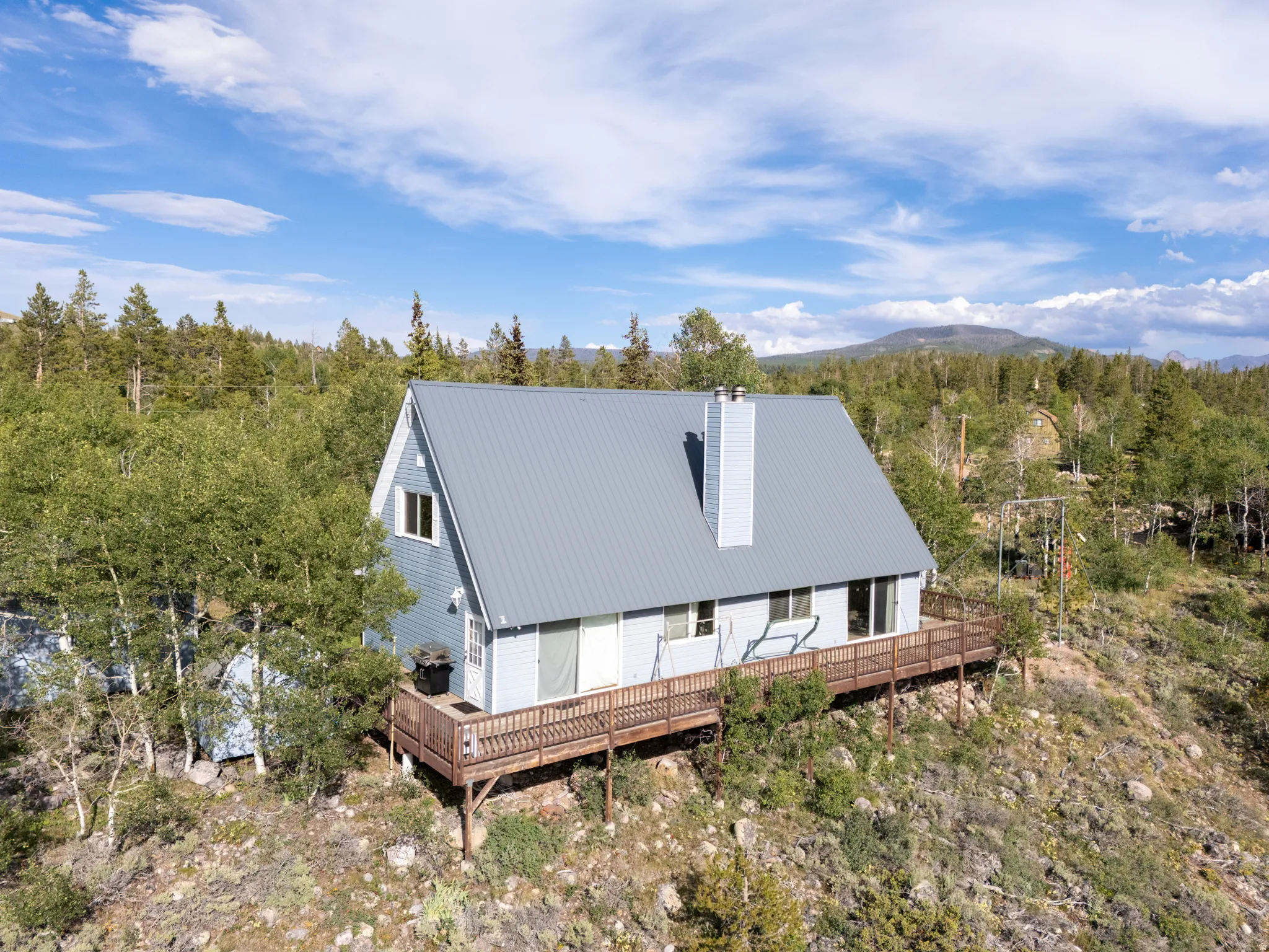 A-frame style residence with light blue siding and a gray metal roof