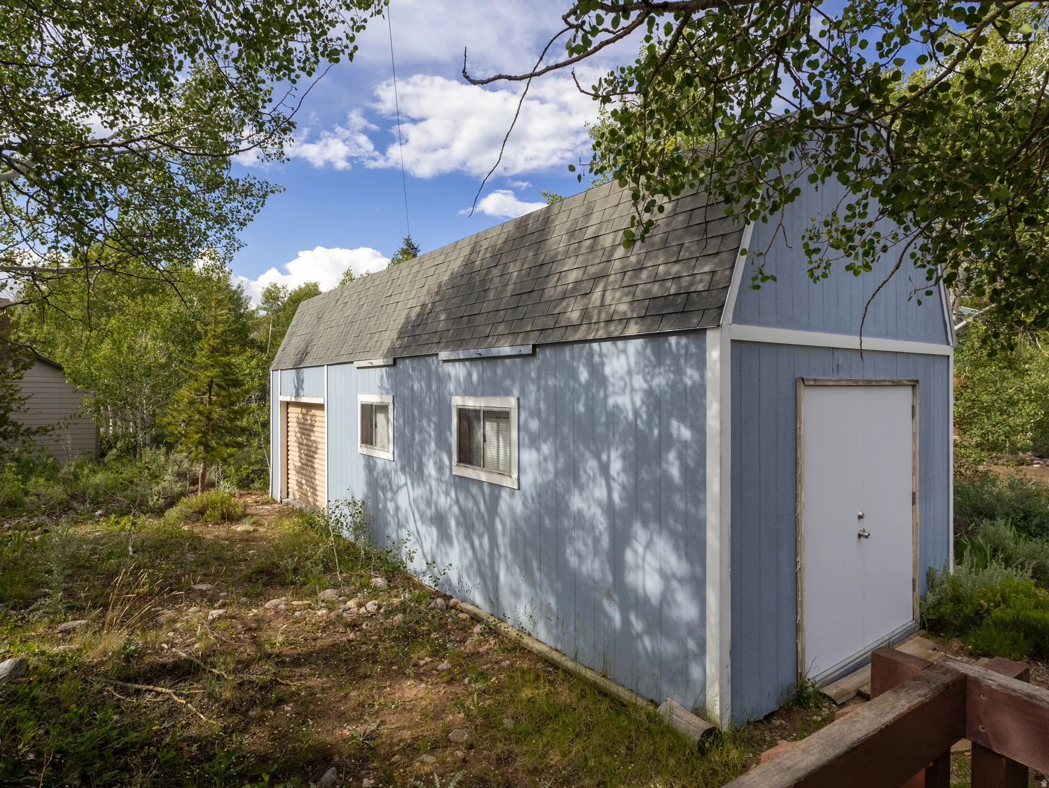 Barn-style auxiliary building featuring a gambrel roof and light blue exterior siding