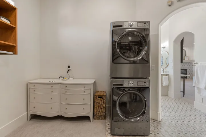 Dedicated laundry area featuring stacked stainless steel appliances and a neutral color palette