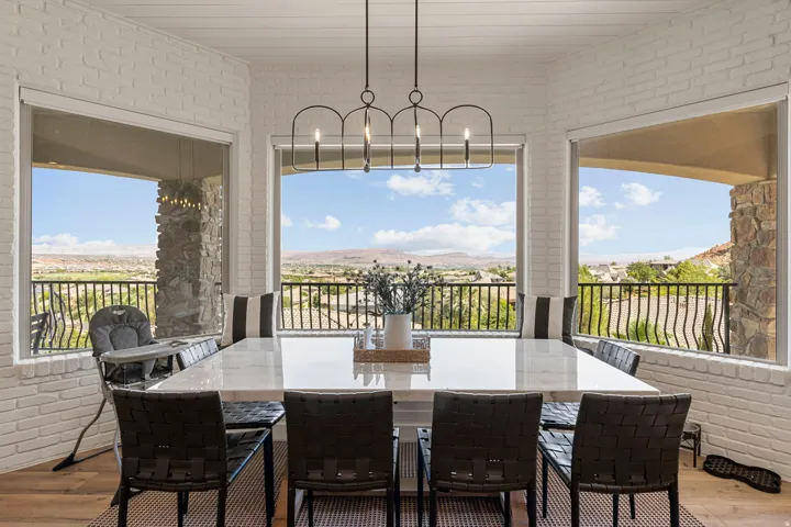 Dining area featuring a large rectangular table with a light-toned surface, surrounded by black chairs