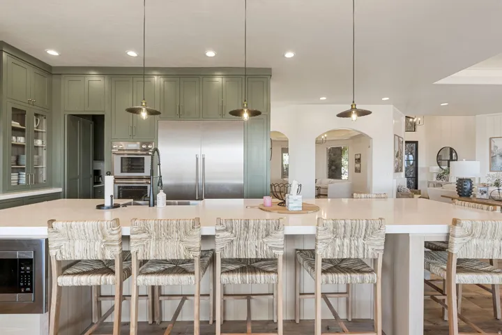 Spacious kitchen featuring a large central island with integrated microwave, abundant cabinetry, stainless steel refrigerator, and built-in double ovens
