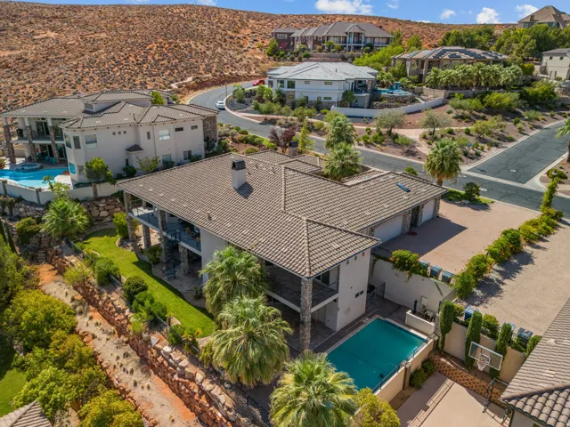 Multi-level residence featuring a tile roof, multiple balconies, a covered pool, and a paved sport court