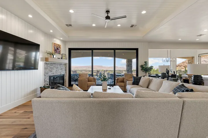 Spacious living area featuring a wood-finish flooring, a contemporary fireplace with a stone surround and wood mantle, and white shiplap accent walls