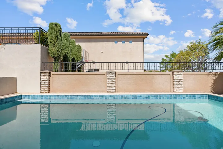 Swimming pool with blue mosaic tile border and integrated cleaning system