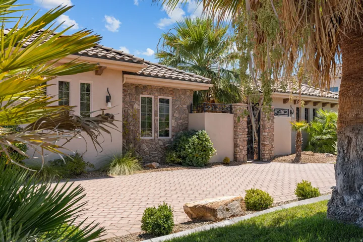 Exterior featuring a paver driveway, stone accents, stucco siding, and a tiled roof