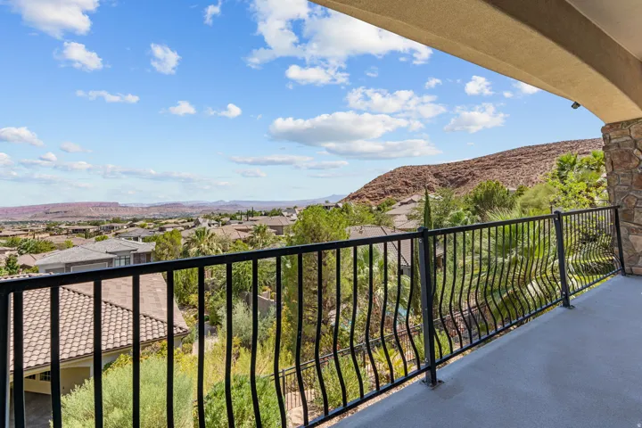 Curved balcony featuring a stone pillar, wrought iron railing, and expansive mountain scenery