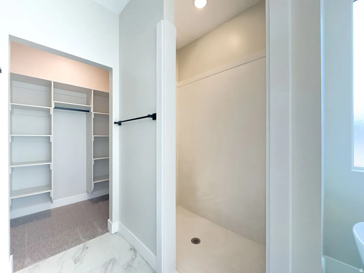 Walk-in shower with a built-in shelf and a drain, featuring a frosted window for privacy