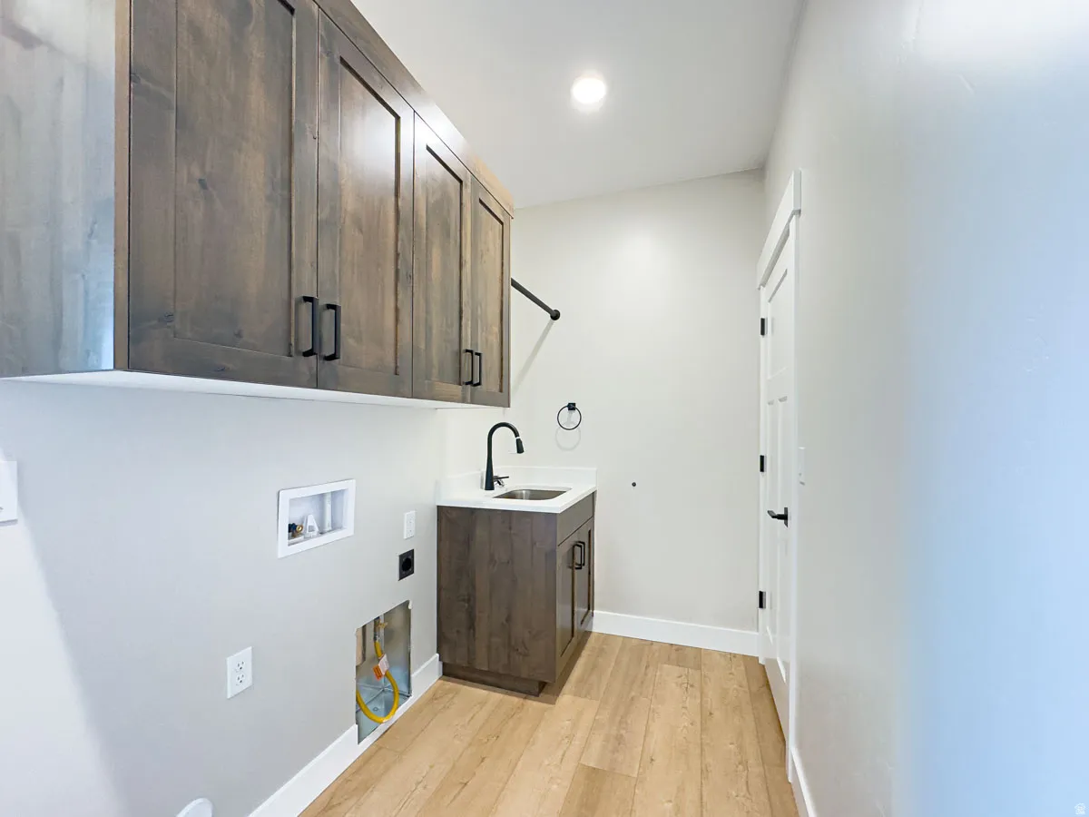 Laundry room featuring wood-finish flooring, white baseboards, and light gray walls