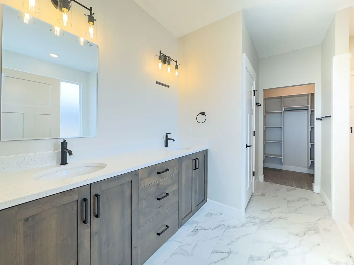 Dual vanity with wood-finish cabinetry, white countertops, and matte black fixtures