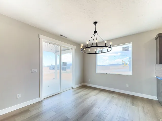 Open-concept room featuring wood-finish flooring, a contemporary chandelier, a sliding glass door to an outdoor covered patio, a large picture window, and neutral wall tones