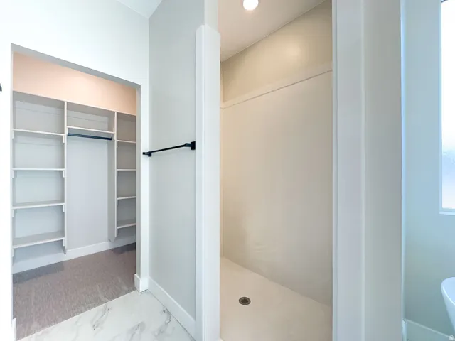 Walk-in shower with a built-in shelf and a drain, featuring a frosted window for privacy