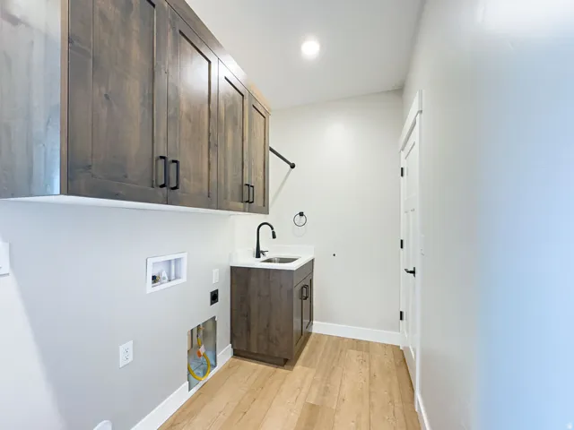 Laundry room featuring wood-finish flooring, white baseboards, and light gray walls