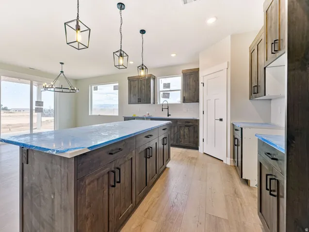 Kitchen featuring a large island with dark wood-finish cabinetry, a white subway tile backsplash, and light wood-finish flooring