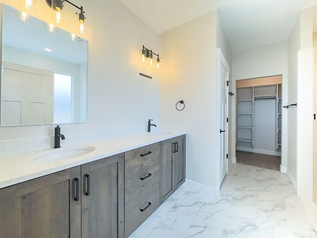 Dual vanity with wood-finish cabinetry, white countertops, and matte black fixtures