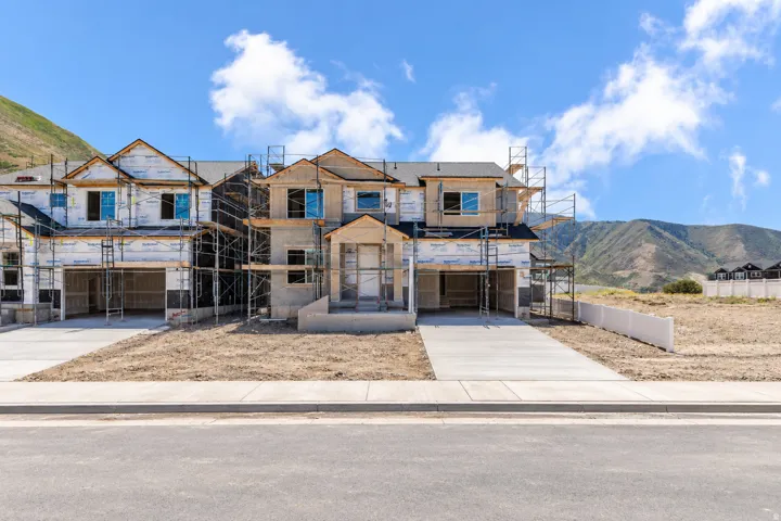 Newly constructed townhomes featuring multi-level design, attached garages, and concrete driveways