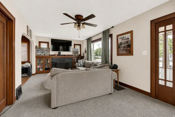 Living room featuring light-colored carpeting, a ceiling fan, and multiple windows