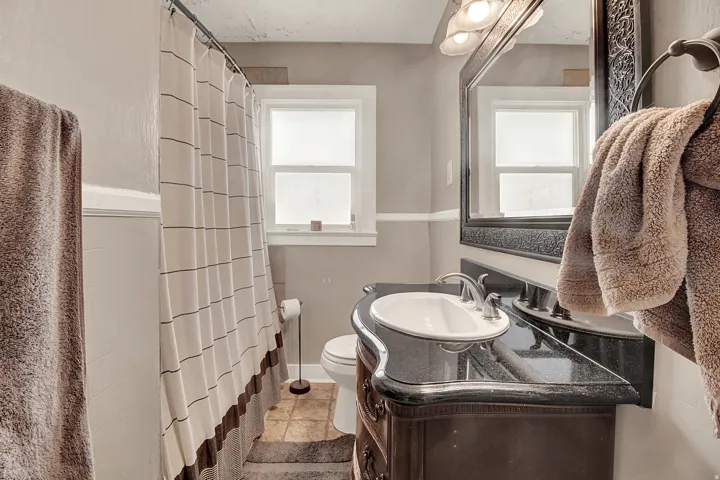 Bathroom featuring a dark wood vanity with an integral sink, dark countertop, and brushed nickel faucet
