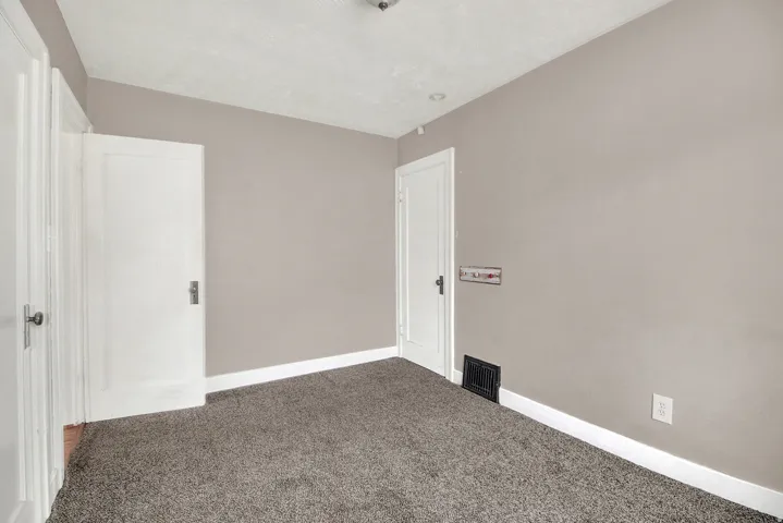 Carpeted interior space featuring light-toned walls, white trim, and multiple white doors