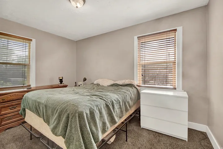 Neutral-toned walls with two windows featuring wood-finish blinds and white trim