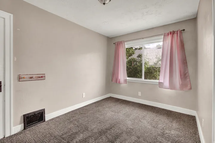 Light-filled room featuring neutral wall paint, white trim, and dark carpeting