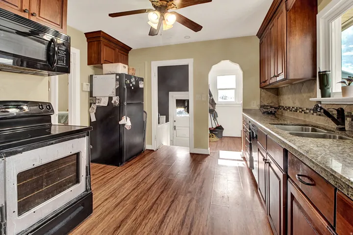 Kitchen featuring wood-finish flooring, dark wood cabinetry, and stone countertops