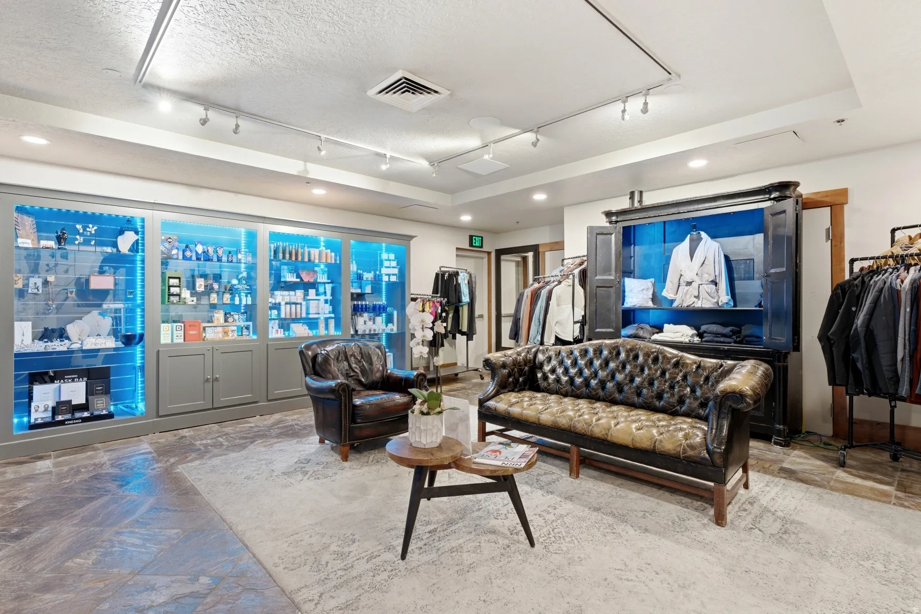 Spacious interior featuring a large accent wall with built-in display cases, recessed lighting, and a distinct floor covering transition between stone-finish and carpeted areas