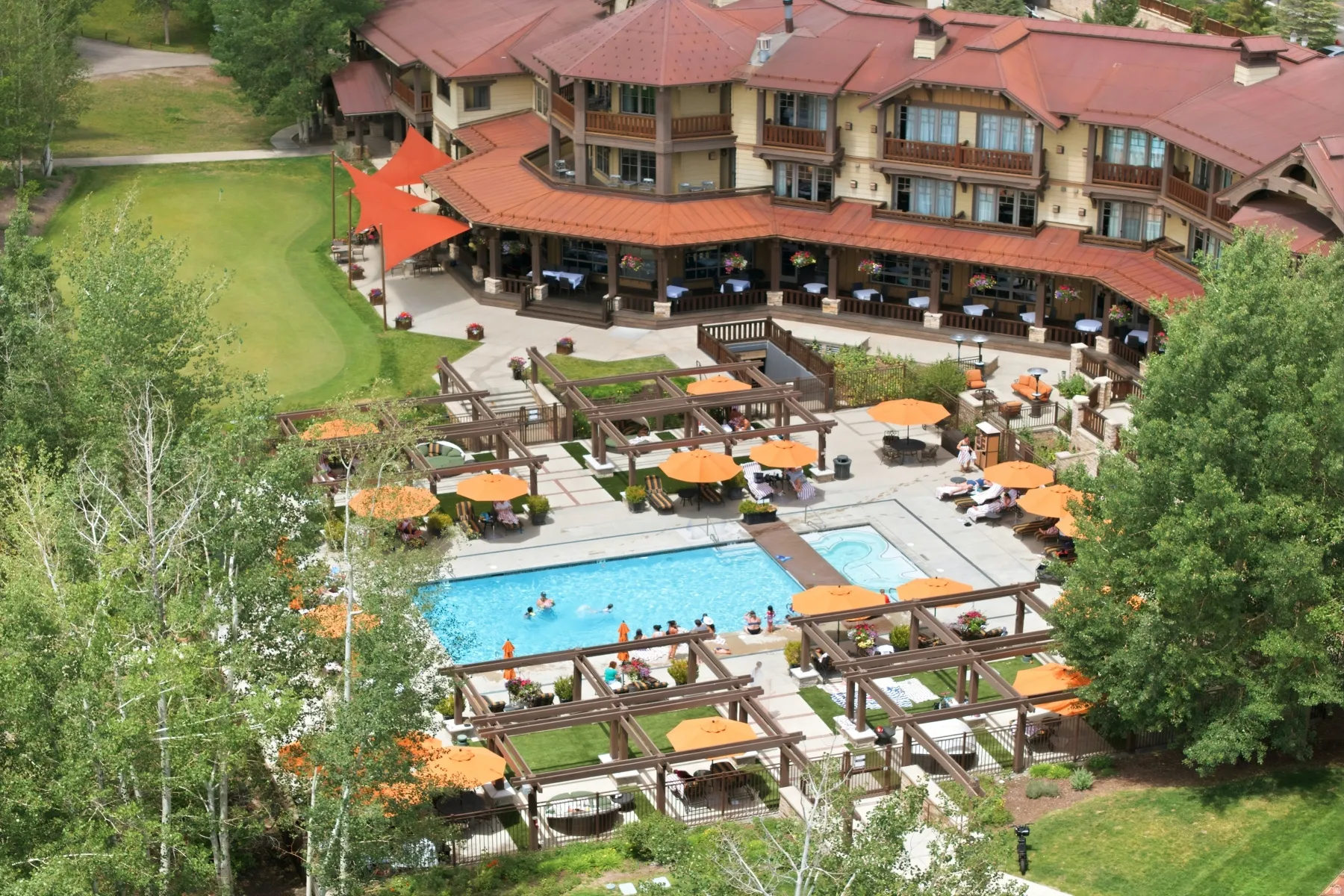 Resort-style outdoor area featuring a swimming pool, surrounding patio, multiple pergolas, and a manicured putting green