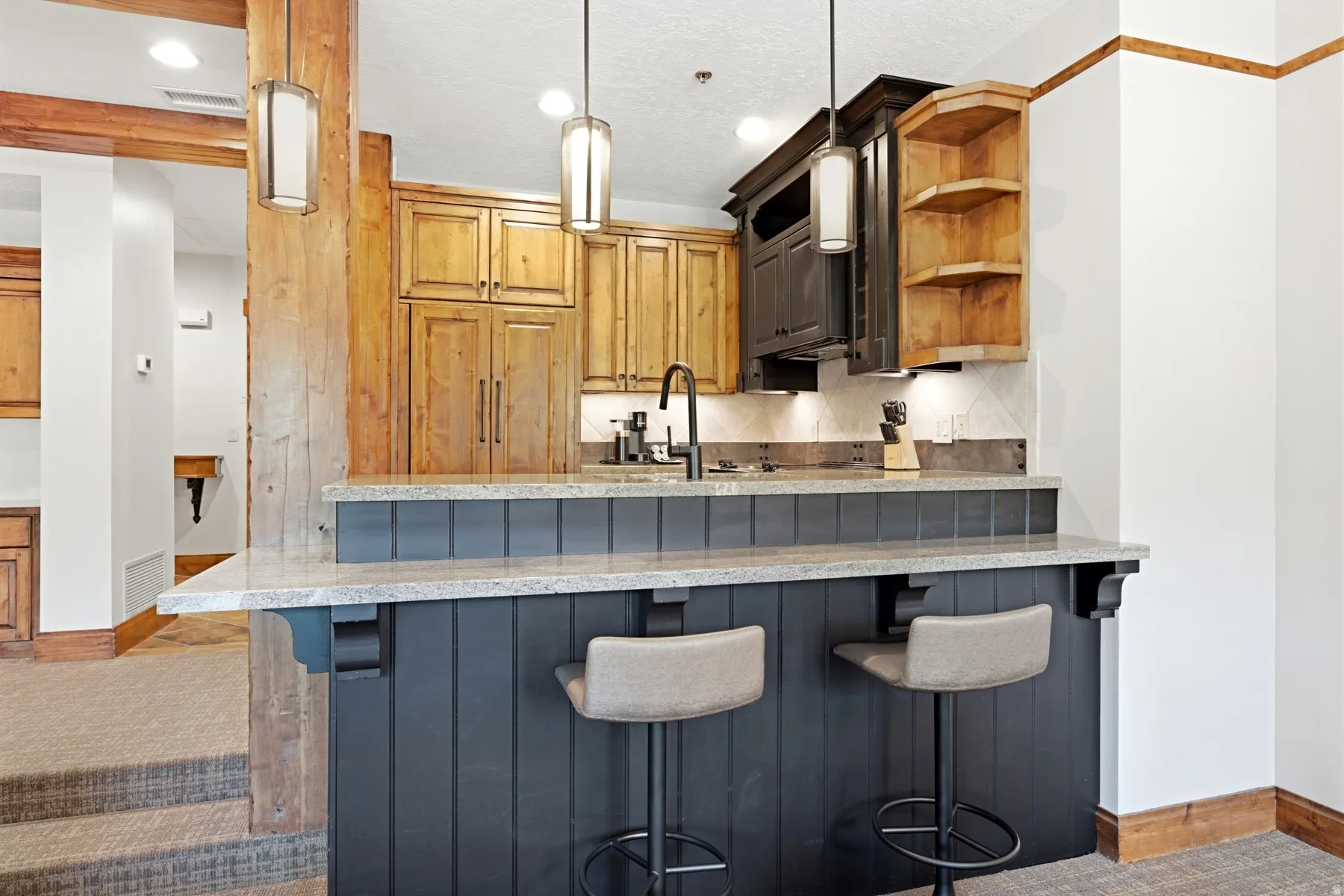 Built-in bar featuring a quartz-finish countertop, black beadboard paneling, and pendant lighting