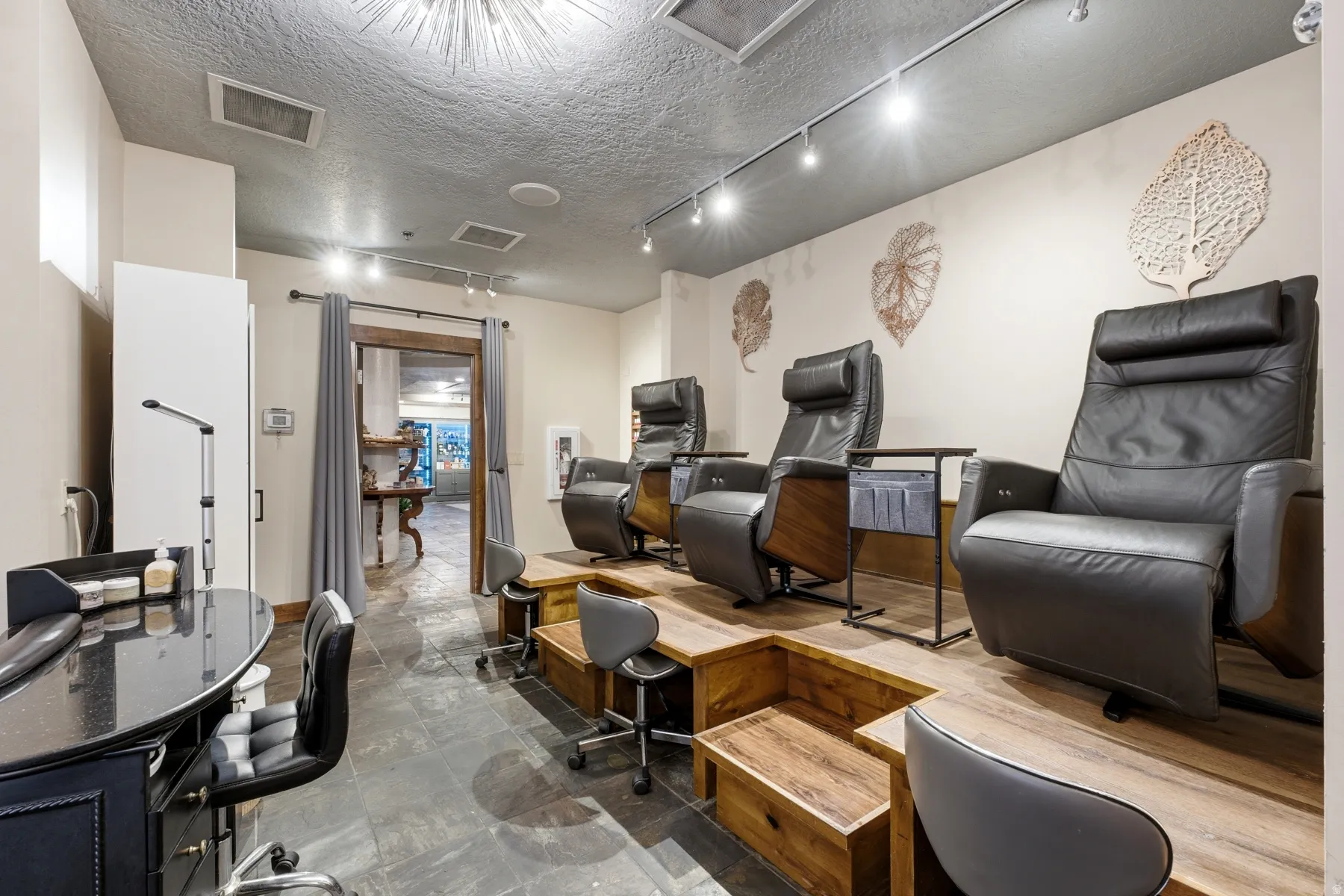 Commercial space featuring dark slate tile flooring, elevated wood-finish platforms, and recessed track lighting