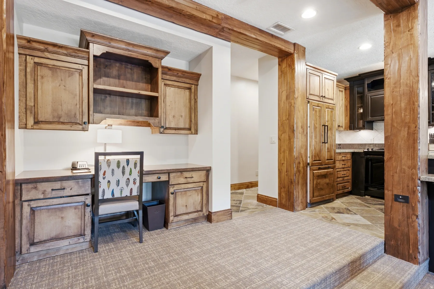 Built-in wood-finish desk with upper cabinetry and shelving