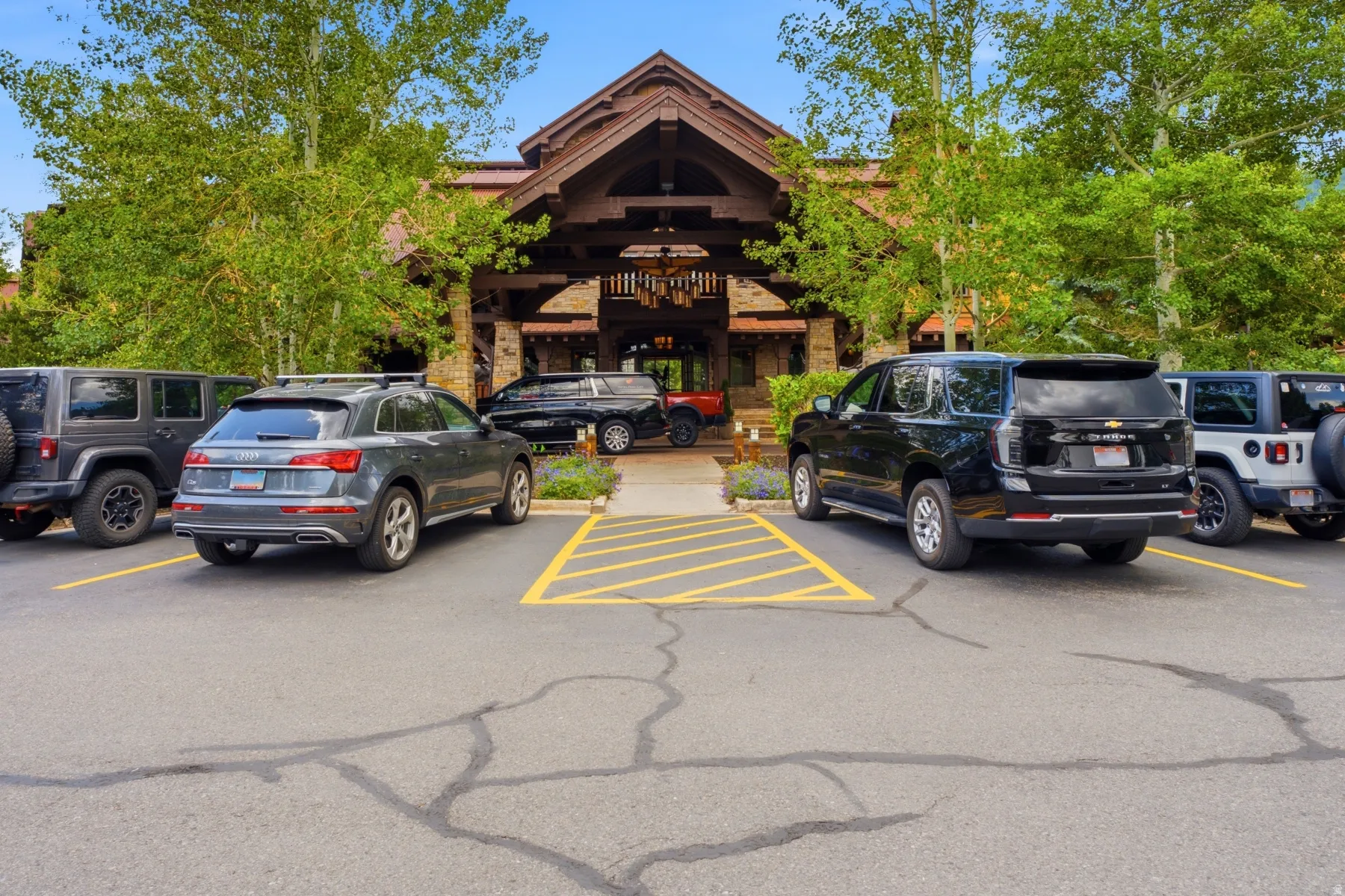Lodge-style building featuring a stone and timber facade, gabled roofline, and prominent porte-cochère entrance