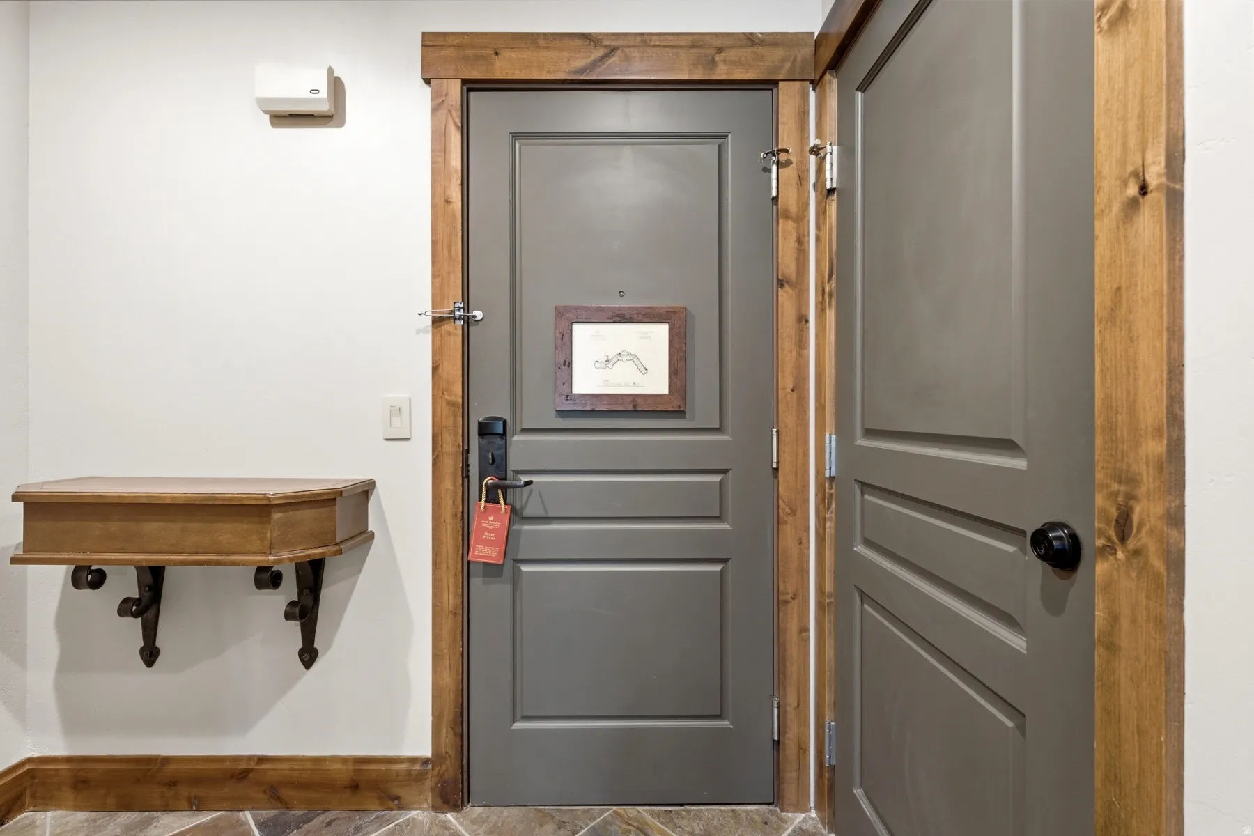 Entryway featuring two paneled doors with dark hardware, framed by natural wood trim