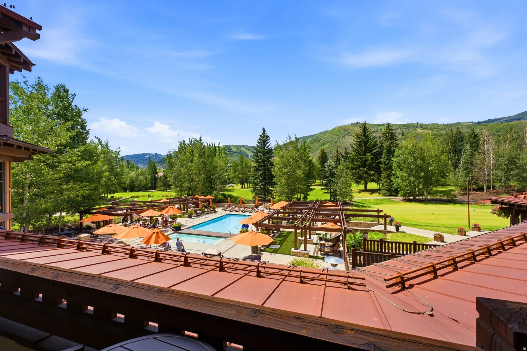 Expansive outdoor swimming pool area with numerous lounge chairs and orange umbrellas