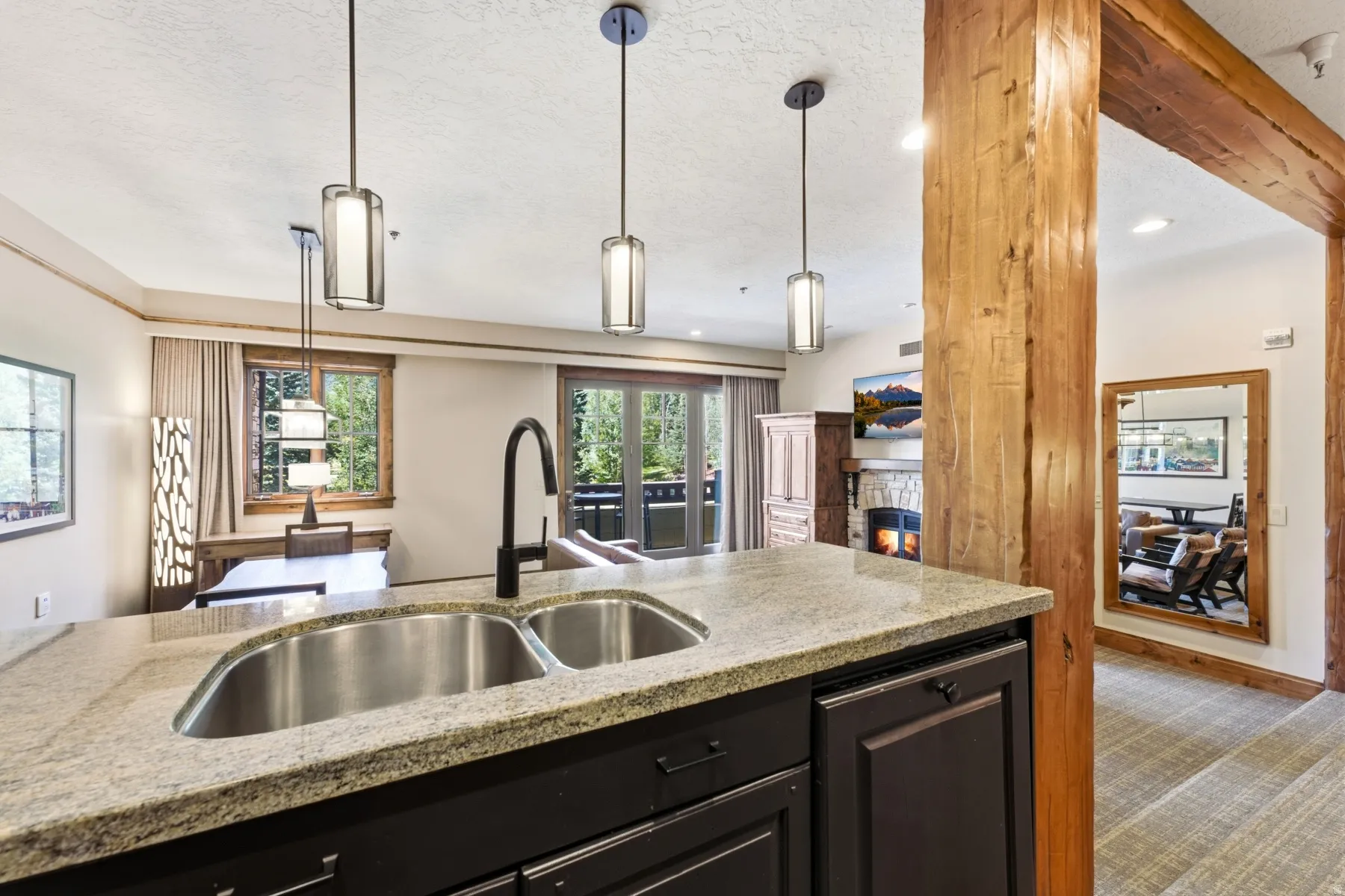 Kitchen island featuring a dual basin sink, gooseneck faucet, and stone countertop