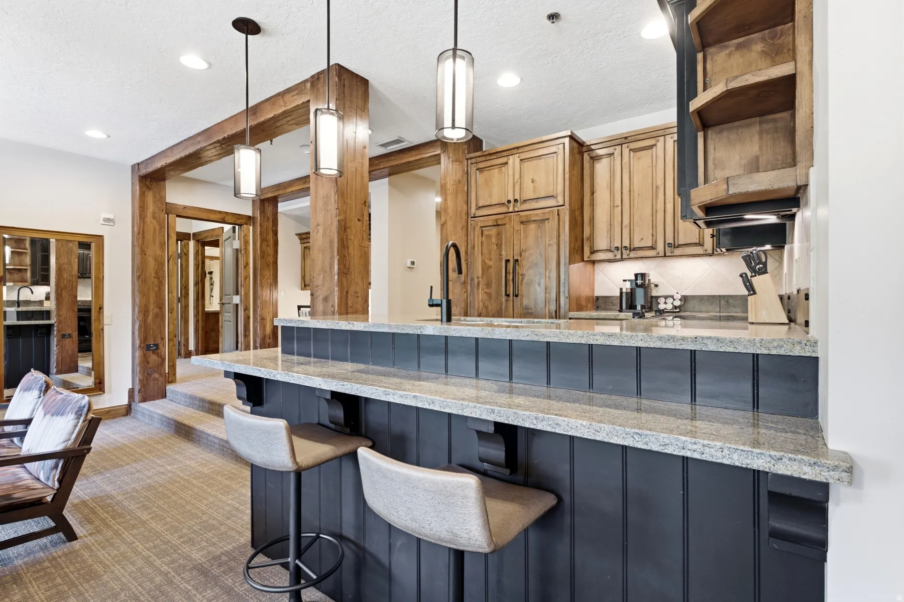 Kitchen bar featuring a light-toned granite countertop, beadboard paneling, and pendant lighting