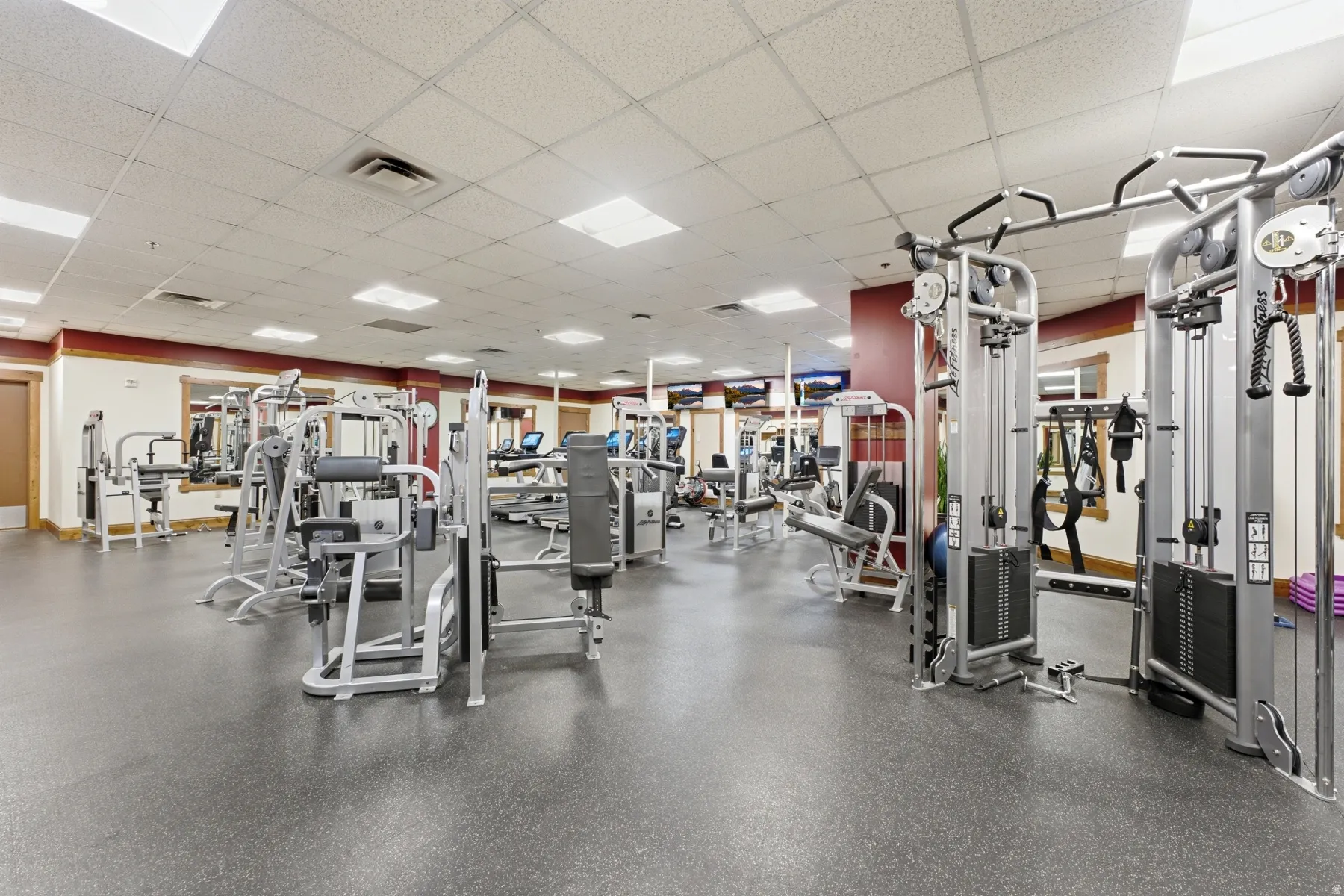 Spacious fitness center featuring rubberized flooring, comprehensive weight machines, cardio equipment, and wall-mounted mirrors