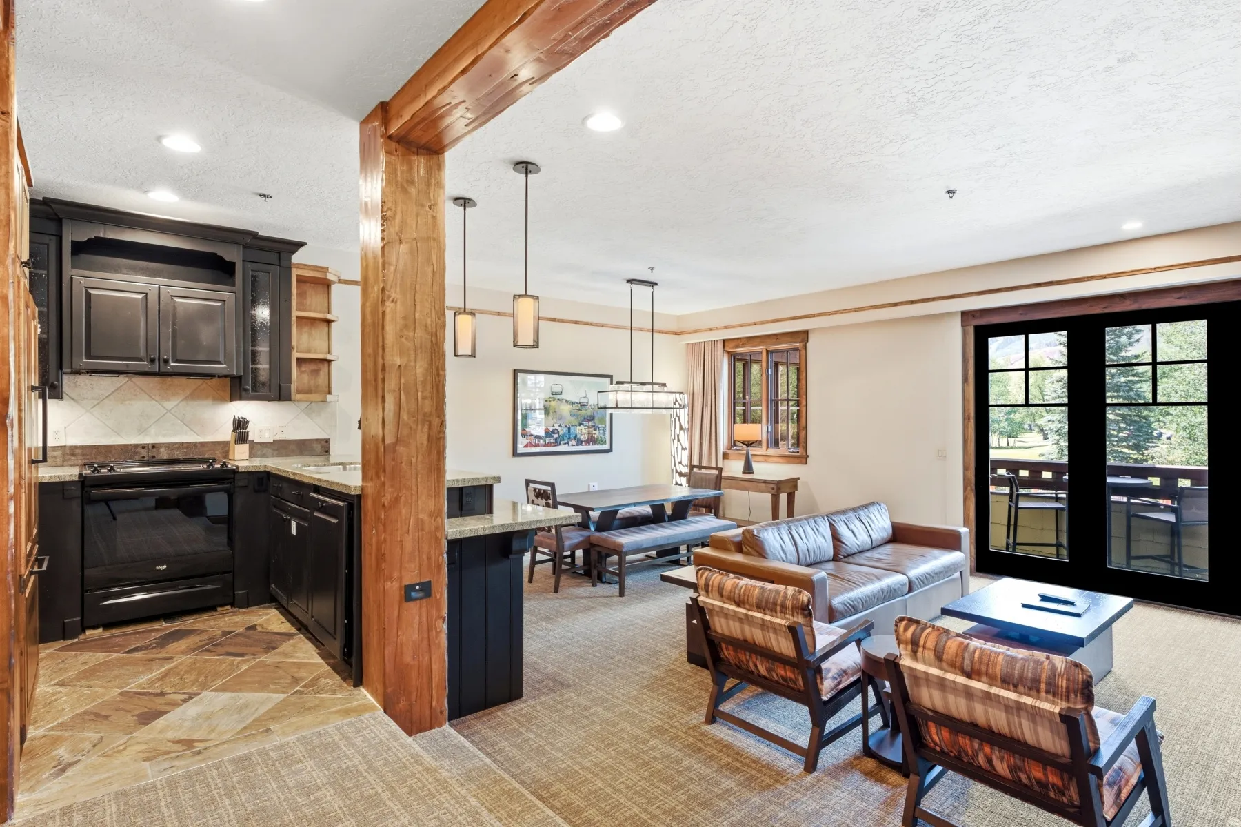 Open-concept living space featuring a kitchen with dark cabinetry, stone countertops, and tile flooring