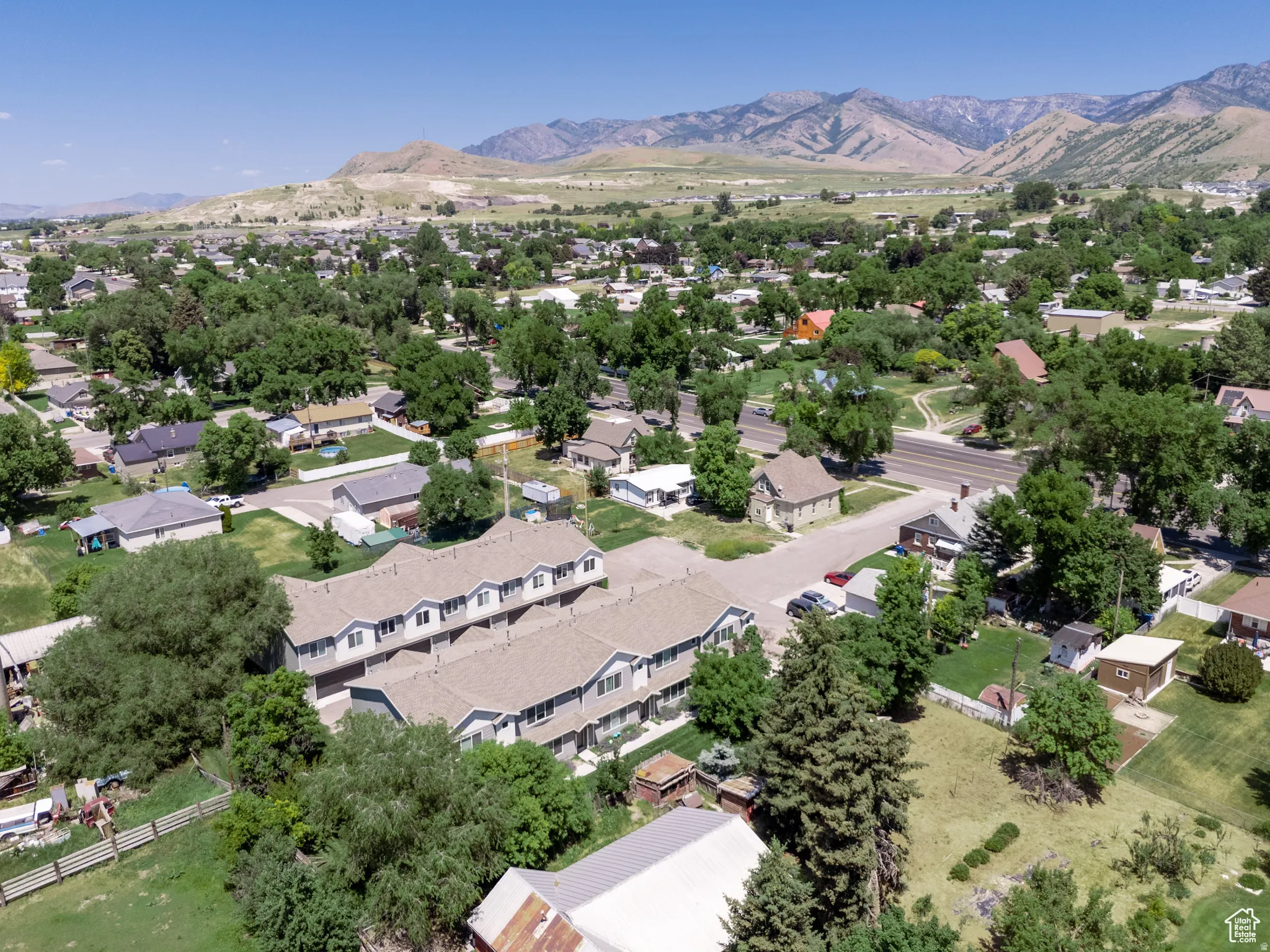 Townhome community situated within a residential area featuring mature trees and a distant mountain backdrop
