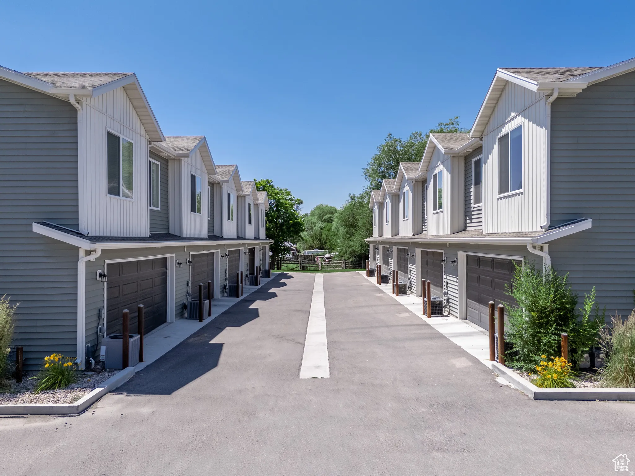 Townhome-style exterior featuring gray siding, white trim, and individual garage doors