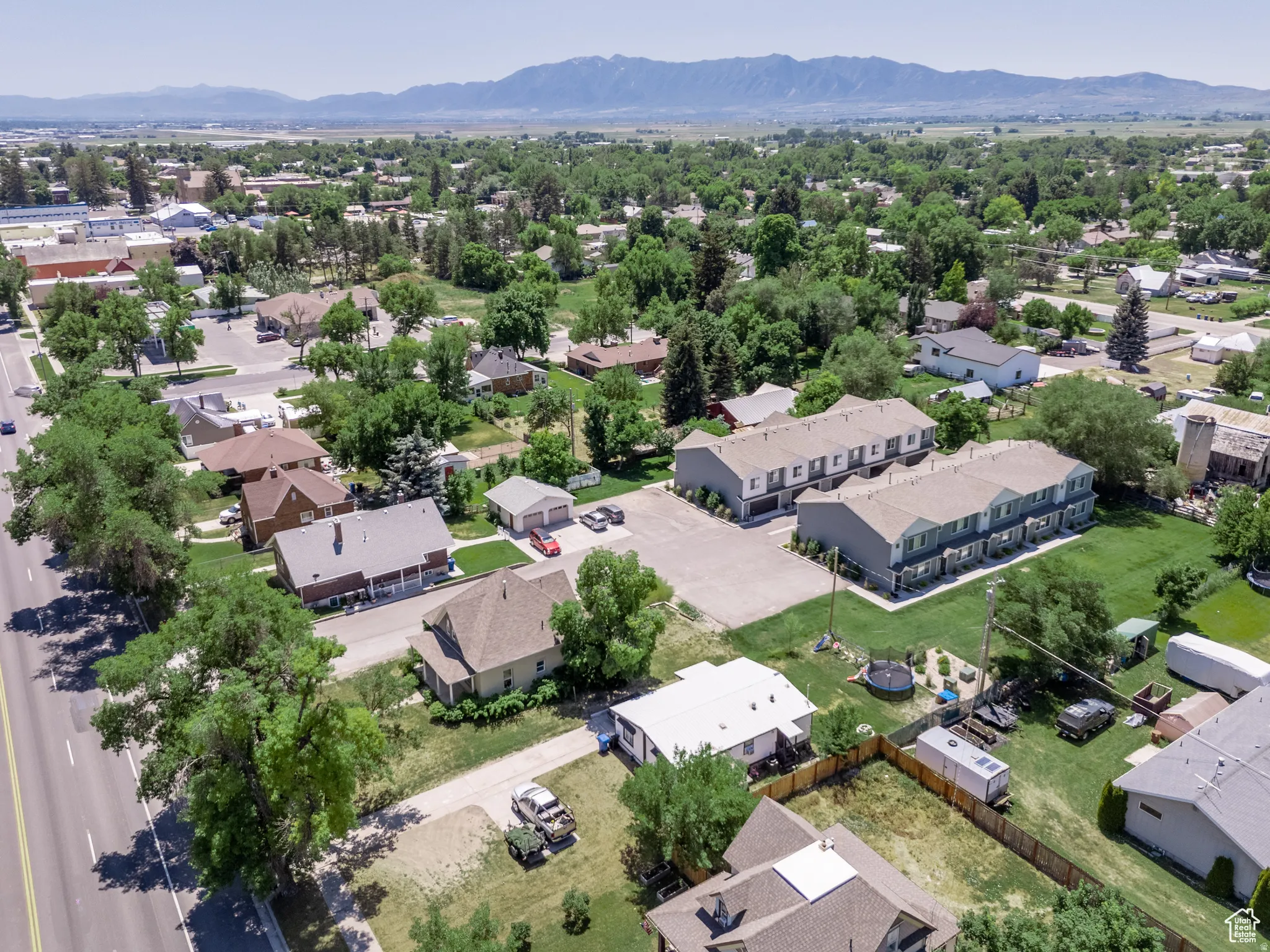 Expansive aerial capturing residential properties, green spaces, and a mountainous backdrop